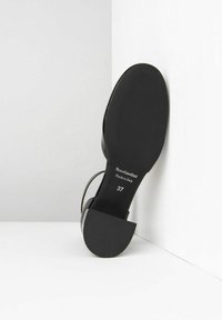 Sandal con tacco nero dal design elegante, caratterizzato da una tomaia liscia, cinturino alla caviglia e una suola rotonda e texturizzata con minimal branding. Taglia 37.