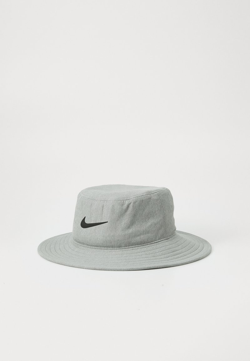 Lys grå bøttehatt laget av teksturert stoff, med en svart Nike-logo på forsiden og en bred, flat brem for solbeskyttelse.