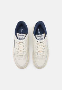 Hvite skinn sneakers med marineblå innside, med perforert tå, matchende snørebånd og Reebok-logo på tungen og siden.