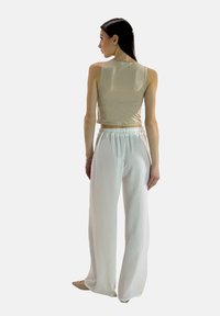 Beige crop-top kombineret med hvide brede bukser. Stoffet ser blødt ud med en struktureret overflade og en elastisk talje.