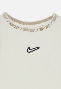 Εκρού ριμπ αμάνικη μπλούζα με στρογγυλή λαιμόκοψη, που διαθέτει μπεζ λωρίδα με λογότυπο και μαύρο λογότυπο Swoosh στο στήθος. Λείο ύφασμα.