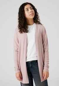 Cardigan rosa chiaro realizzato in un morbido tessuto texturizzato. Design con apertura frontale e maniche lunghe. Indossato sopra una t-shirt bianca e jeans.