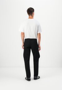 Sorte cargo bukser med sidelommer og en afslappet pasform, parret med en ensfarvet hvid t-shirt. Glat stof med et klassisk design.