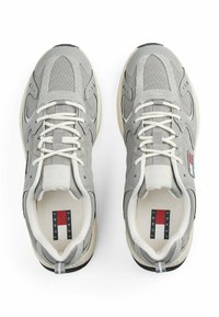 Szare buty sportowe z siateczkowej i tekstylnej cholewki, kontrastującą gumową podeszwą i tonacjami sznurowadeł. Metka z logo na wkładce z czerwonymi i niebieskimi akcentami.