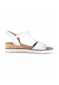 Sandale en cuir blanc avec un talon en liège, présentant un design à T, une bride arrière réglable et une semelle blanche texturée.