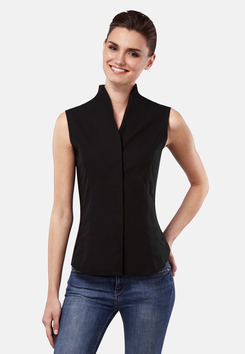 Haut sans manches noir avec un col haut, design ajusté, texture lisse et coutures visibles associé à un jean bleu foncé.