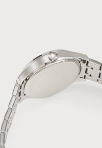 Montre-bracelet en acier inoxydable avec finition polie, boîtier rond et couronne texturée. Bracelet de style avec une fermeture sécurisée.