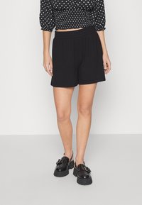 Svarta ribbade shorts med elastisk midjeband, ihop med en svart prickig crop top och svarta plattformsskor.