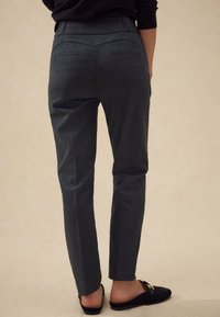 Pantaloni sartoriali a quadri neri e grigi, vestibilità slim, con vita a mezza altezza, tasche posteriori e tessuto liscio. Abbinati a scarpe slip-on nere.