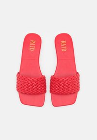 Sandales plates rouges avec une large sangle tissée et une semelle plate, présentant une finition lisse et un logo embossé doré sur la semelle intérieure.