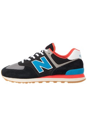 Vue latérale d'une chaussure de sport noire et grise avec un logo bleu, des lacets blancs, une doublure intérieure rouge et une semelle en caoutchouc.