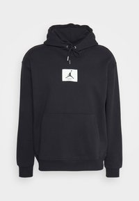 Sweat à capuche noir avec poche avant et cordon de serrage à la capuche, avec un patch carré blanc représentant la silhouette d'un joueur de basketball et le mot « Flight ».