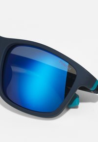 Occhiali da sole a specchio blu con montatura scura e accenti turchesi. Presentano una forma avvolgente e superfici testurizzate sulle aste.