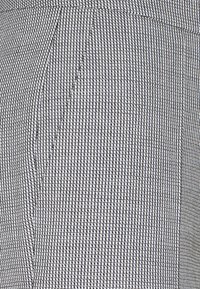 Grå och vit vävd tyg med ett rutmönster, med en slät textur och strukturerad design, lämplig för skräddarsydda kläder.