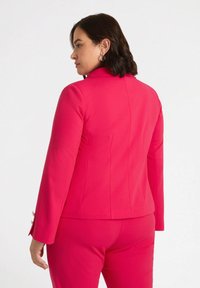 Dopasowana marynarka w jasnoróżowym materiale z klasycznym kołnierzykiem, wyprofilowanymi ramionami i guzikami na rękawach, oferująca urzekaący krój.