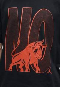 Έντονο κόκκινο «ΟΧΙ» με κόκκινο ταύρο μπροστά, σε μαύρο φόντο, μικρό λογότυπο Jumpman κάτω δεξιά.