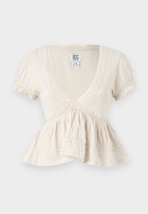 Kortærmet bluse med V-hals i cremefarvet stof, med rynkede ærmer, knyttet talje og tekstureret krop. Har blondekanter og peplumnederdel.