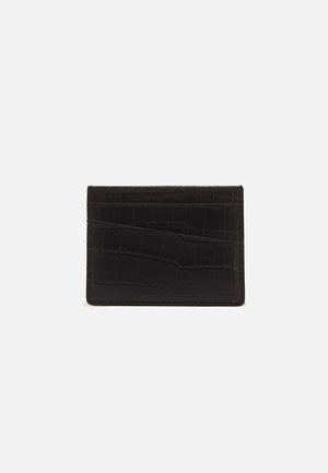 Porte-cartes en cuir noir avec texture crocodile, comportant plusieurs fentes horizontales et diagonales sur un fond blanc uni.