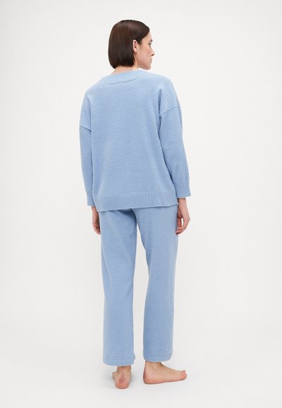 Fleece loungewear set in light blue; oversized sweater with ribbed hem, long sleeves, and matching pants; soft texture, relaxed fit.