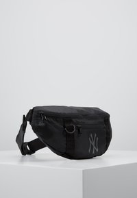 Sac banane en nylon noir avec fermeture éclair, poche avant et détail de logo gris. Comprend une sangle ajustable et un tissu texturé.