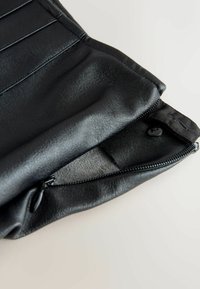 Schwarze Leder-Clutch mit strukturiertem Oberflächenmaterial, Reißverschluss und glattem Innenfutter. Akzentuiert mit einem Knopfdetail in der Nähe der Öffnung.
