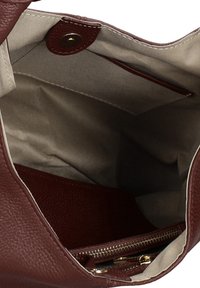 Sac à main en cuir marron ouvert montrant un intérieur en tissu beige avec une fermeture magnétique et une poche intérieure zippée.
