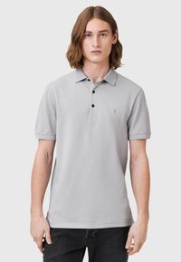 Lichtgrijze polo shirt van katoen, met een knoopsluiting van drie knopen, korte mouwen en een klein geborduurd logo op de borst.