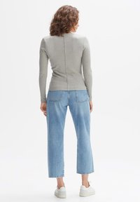 Grey long-sleeve top with a center seam, paired with light blue wide-leg jeans. The outfit features a relaxed fit and soft fabric texture.