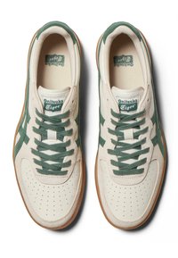 Białe skórzane trampki z zielonymi zamszowymi akcentami, perforowanym przodem i zielonymi sznurowadłami. Podeszwa z gumy oraz logo marki na języku.