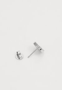 Boucles d'oreilles en argent en forme ronde avec une surface polie et un tige lisse, accompagnées d'une pince pour un maintien sécurisé.