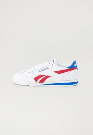 Hvid Reebok sneaker med røde striber, blå hæl-detalje og logo på siden og tungen, vist fra ydersiden på en ensfarvet baggrund.