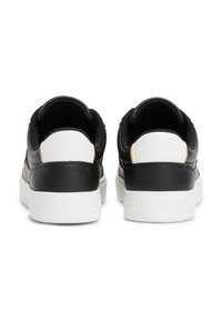 Fekete-fehér tornacipők texturált hátsó sarokkal, sima bőr és szövet felsőrésszel, valamint márkajelzéssel ellátott fehér gumitalppal.