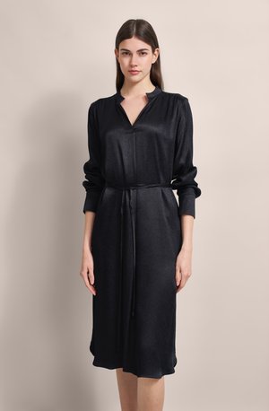 Black dress with long sleeves, V-neckline, and a tie belt. Made of a glossy, smooth fabric with a knee-length cut and subtle texture.