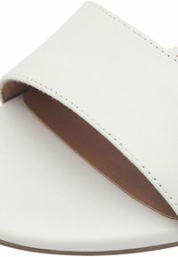 Vit läder flip-flop med bred rem och synlig söm över en brun innersula och rund tå.