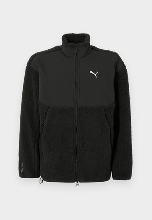 Giacca in pile nera con sezione superiore liscia, colletto alto, chiusura con zip e logo Puma. Presenta materiale strutturato e tasche laterali.