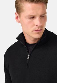 Mustmust mustrikk, mis on valmistatud tekstuuriga kudumist. Omab lühikest tõmblukk ja sobivat kraed. Lihtne ja klassikaline disain.