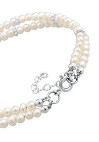 Dreisträngiger Perlenarmband mit weißen Perlen, silbernen Akzenten und einem Verschluss mit Kettengliedern. Glatte Textur, elegantes Design.
