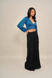 Kékeszöld hosszú ujjú átvetős felső fekete bő szárú nadrággal párosítva. Sima anyag, rövidített fazon mély V-nyakkivágással. Egyszerű, elegáns sziluett.