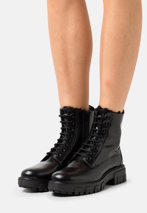 Sorte læder snørestøvler med en kraftig sål, der har en tekstureret kant, metaløjer og en lynlås i siden for nem adgang.