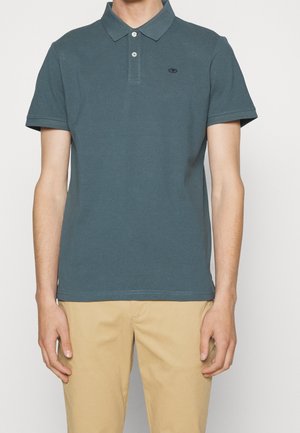 Polo bleu sarcelle en coton avec un col classique, une patte de boutonnage à deux boutons, des manches courtes et un logo brodé sur le côté gauche.