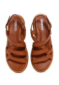 Brown leather sandals with multiple crossed straps, perforated footbed, and adjustable ankle strap. Flat sole with slight arch support.