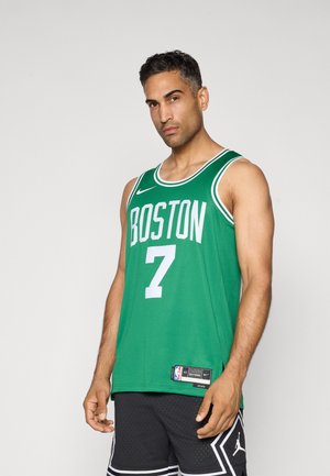 Hombre con camiseta verde de baloncesto de Boston con el número 7 y pantalones cortos negros, de pie contra un fondo claro y plano.