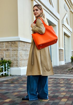 Borsa a spalla in pelle arancione brillante con finitura a granuli e hardware in argento. La borsa ha un design morbido e senza motivi visibili.