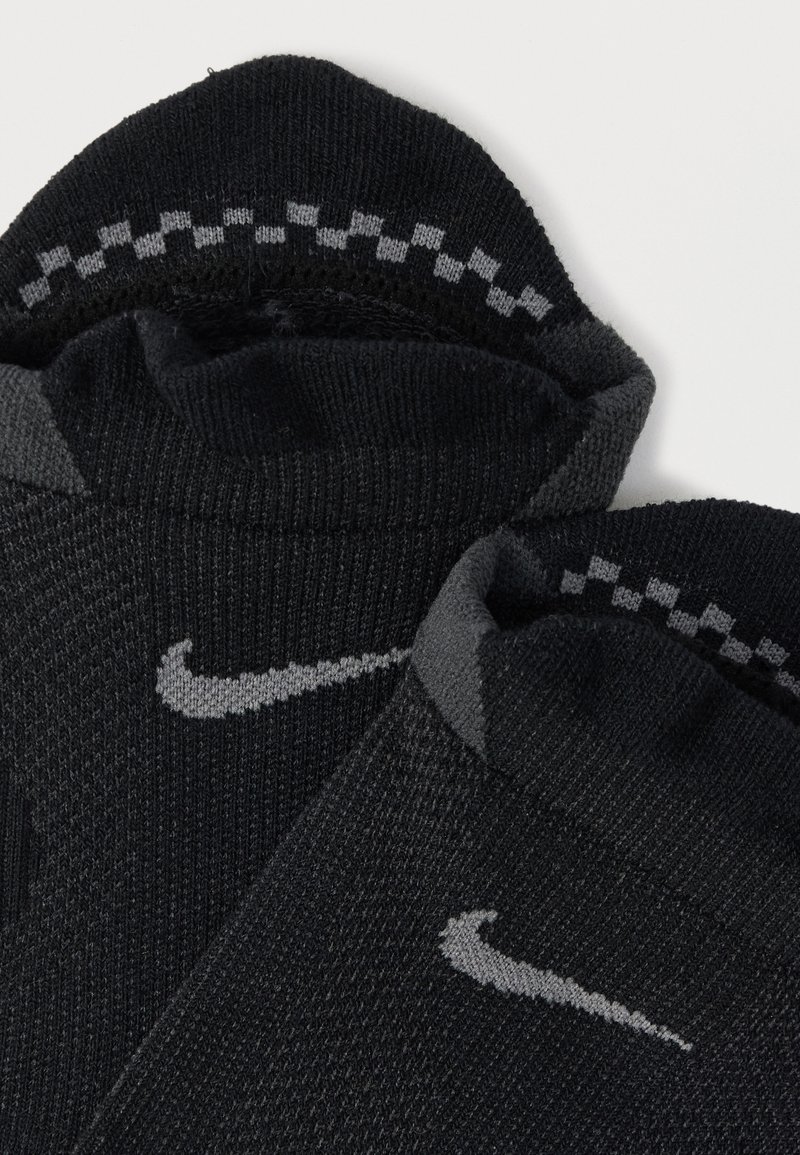 Black socks with a textured knit, featuring a grey Nike logo and a patterned gray band at the top.