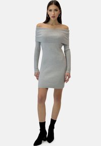 Grå off-shoulder ribstrikket kjole med lange ærmer, kropsnær pasform og længde til midt på låret, kombineret med sorte ankelstøvler.