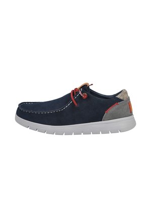 Zapato de ante azul marino con detalles grises, costuras blancas, cordones rojos y suela exterior gris, con un panel trasero texturizado y diseño minimalista.