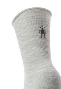 Calzino grigio lavorato a maglia con texture a coste, con un piccolo design grafico nero di una figura vicino alla cima.