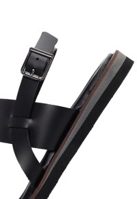 Black leather sandal featuring a wide cross-strap design, adjustable buckle, and a contrasting layered platform with gray and brown accents.