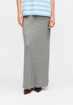 Grå, knælængde strikket nederdel med blød tekstur, kombineret med spidse bordeaux hæle. Outfit'et fuldendes af en blå top med vandrette striber.