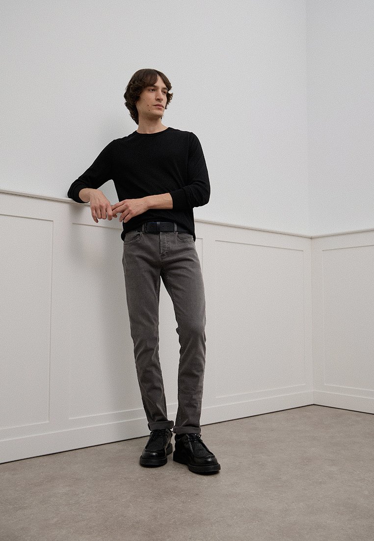 Graue Slim-Fit-Hosen mit normalem Bund, getragen mit einem schwarzen Langarmhemd und schwarzen Schnürschuhen. Glatte Stoffoberfläche.